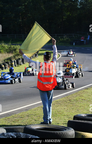 Eine Sicherheit Marshall hält eine gelbe Fahne bei einem Go-Kart-Rennen Stockfoto