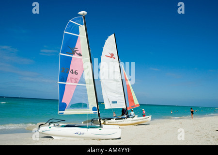 Kleine Segeljollen mit bunten Segeln sitzen auf dem weißen Sand, die darauf warten, von Abenteuertouristen, Varadero Beach gemietet werden Stockfoto