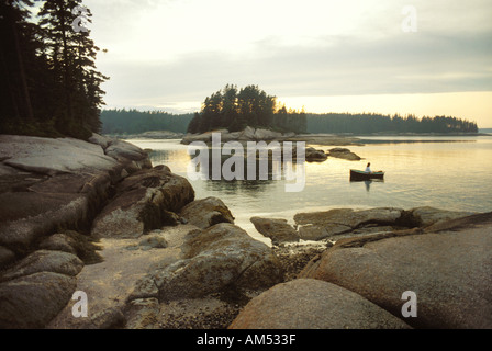 Frau Rudern an Land auf einer Insel im Penobscot Bay Küste Maines. Ihr Segelboot ist verankert in der Nähe. Stockfoto