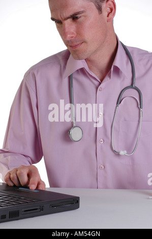 Ein junger männlicher Arzt an seinem Schreibtisch mit einem Laptopcomputer Stockfoto