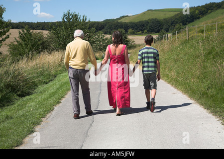 Drei Generationen der Familie gehen in die Ferne entlang Landstraße Rockley, Wiltshire, England Stockfoto