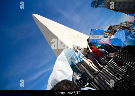 Fußball-Fußball-Fans singen und jubeln, balancieren gefährlich auf einen scharfen Zaun um den Obelisken argentinischen Fahnen schwenkten. Stockfoto