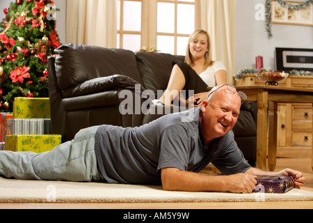 Reifer Mann in der Weihnachtszeit auf Teppich liegend, lachen Stockfoto
