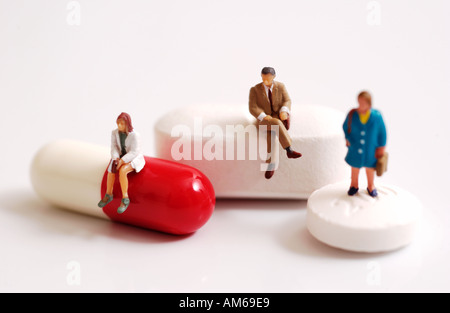 Drei winzige Figuren stehend und sitzend auf Pillen Stockfoto