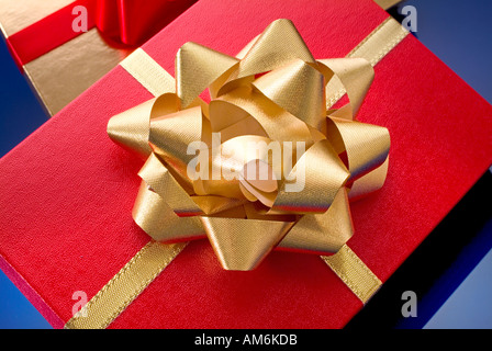 Nahaufnahme von roten Geschenk-Box mit großen goldenen Bogen und gold Geschenk-Box mit rotem Band im Hintergrund Stockfoto