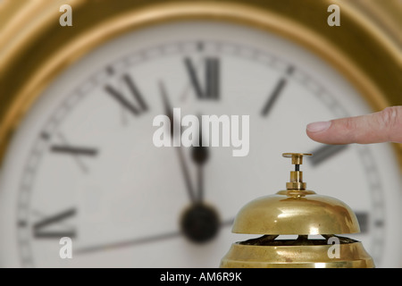 Schreibtisch-Glocke mit einer Wanduhr im Hintergrund Stockfoto