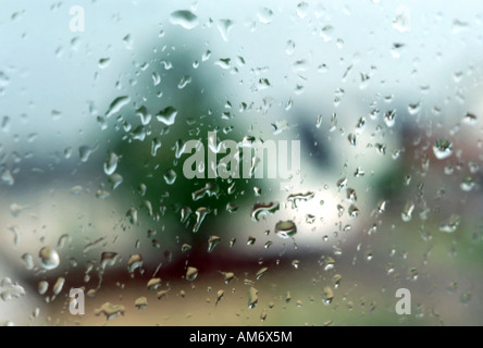 Durch ein Fenster im oberen Stock in einem trockenen Haus schießen heraus in den durchnässten Regen draußen im mid-August. Sommerregen sind so erfrischend. Stockfoto