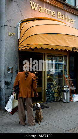 Frau mit Hund draußen eine Bäckerei, Amsterdam, Niederlande Stockfoto