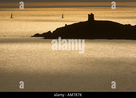 Genuese Turm auf der Punta d'Omigna in der Nähe von Cargese bei Gegenlicht in der Abenddämmerung mit Segelbooten, westliche Küste von Korsika, Frankreich Stockfoto