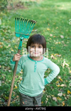 5 Jahre altes Mädchen hält kleine Harke Stockfoto