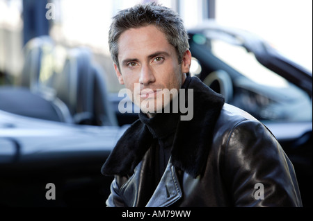 Mann in Lederjacke vor Cabrio Stockfoto