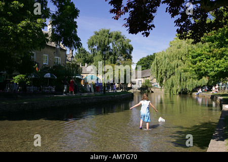 Junges Kind Paddel in flachen Windrush Fluss Zentrum der malerischen idyllischen englischen Cotswolds Dorf Bourton auf die Wasser-UK-GB Stockfoto