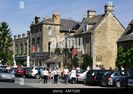 Touristen erkunden die berühmten High Street Souvenir Boutiquen in der schönen Stadt in Cotswold Bourton auf dem Wasser, England UK GB Stockfoto