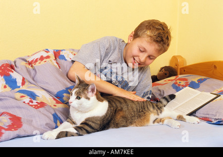 junge und Katze - im Bett liegend Stockfoto