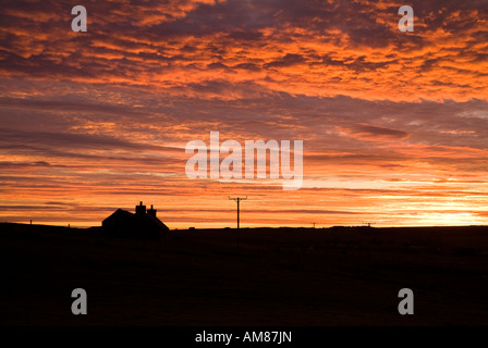 dh ORPHIR ORKNEY Scottish Cottage Silhouette und Wolkenlandschaft Sonnenuntergang Himmel Dämmerung Haus rot orange Wolken croft dramatische Gehöft landschaftlich Schottland Dämmerung Stockfoto