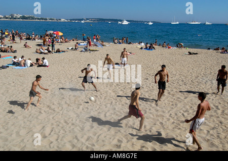 Junge Männer, die Fußball spielen am Strand von La Croisette, Cannes, Frankreich Stockfoto
