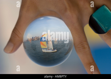 Segelboot in einem Glas, einer Frau mit einer Kugel mit einem Segelboot hinter einander im Glas Stockfoto