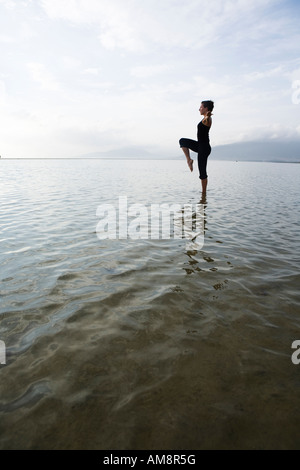 Frau in Balance Pose im Wasser beim Yoga steht Stockfoto