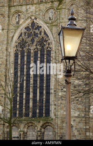 Außerhalb der Kathedrale von Durham ist eine alte altmodischen Stil Straßenlaterne beleuchtet. Die Lampe steht vor ein gewölbtes Fenster. Stockfoto