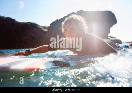 Mann auf Surfbrett im Wasser liegen. Stockfoto