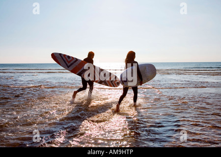 Paar im Wasser trägt, Surfbretter ausgeführt. Stockfoto