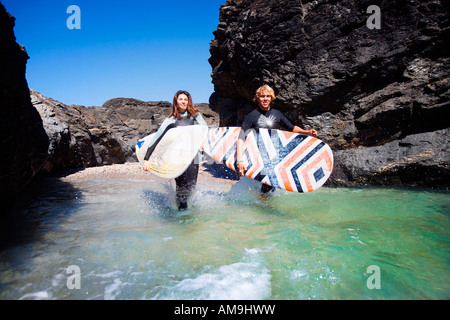 Paar laufen im Wasser mit Surfbrettern Lächeln auf den Lippen. Stockfoto