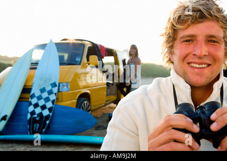 Mann am Strand mit einem Fernglas lächelnd mit Frau entladen van am Strand. Stockfoto