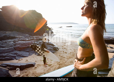 Paar steht am Strand mit Surfbrettern. Stockfoto