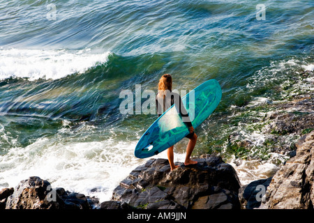 Frau mit einem Surfbrett auf den großen Felsen. Stockfoto