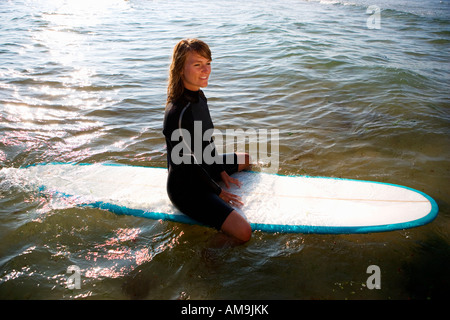 Frau sitzt auf einem Surfbrett Lächeln auf den Lippen. Stockfoto