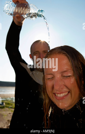Lachende Mann gießt Wasser über den Kopf der Frau. Stockfoto