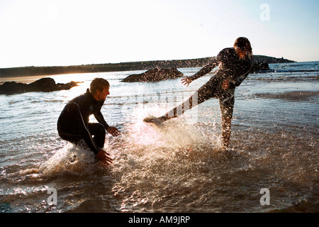 Paar in Neoprenanzüge planschen im flachen Wasser. Stockfoto