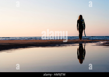 Frau am Strand mit Surfbrett stehend. Stockfoto