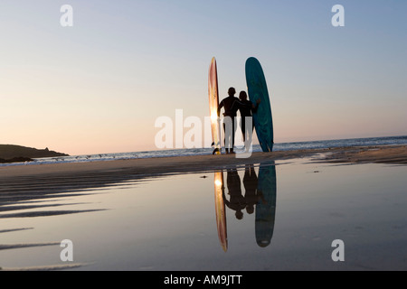 Paar steht am Strand mit Surfbrettern. Stockfoto