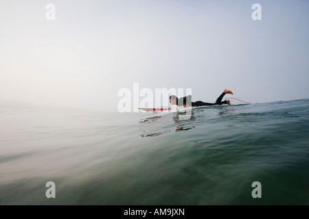 Mann auf Surfbrett im Wasser liegen. Stockfoto