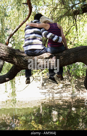 Paar sitzt in einem Baum an einem See. Stockfoto