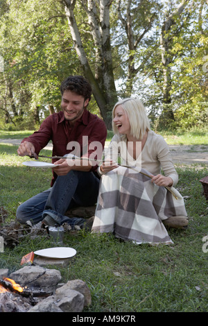 Zu zweit am Campingplatz kochen Hotdogs über der Feuerstelle. Stockfoto