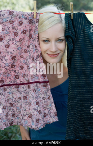 Frau spähen durch Wäsche auf der Wäscheleine Lächeln auf den Lippen hängen. Stockfoto