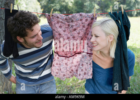 Paar spähen durch Wäsche auf der Wäscheleine Lächeln auf den Lippen hängen. Stockfoto