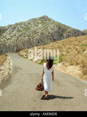 Frau mit Tasche entlang einer Landstraße. Stockfoto