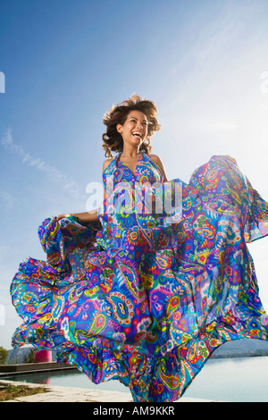 Dynamische Schönheit Frau lachend im Freien in einem bunten langen Sommerkleid. Stockfoto