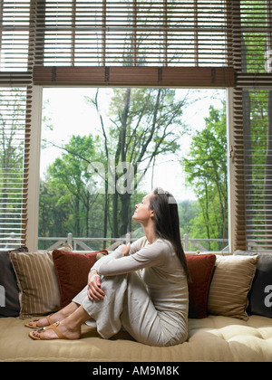 Frau mit Augen geschlossen auf Sofa im Wohnzimmer sitzen. Stockfoto