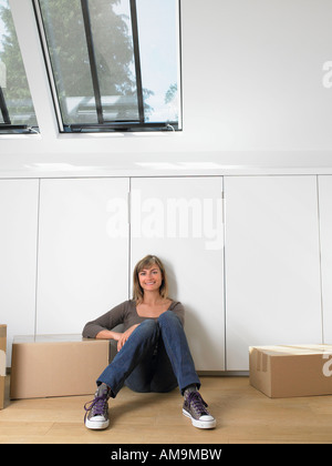 Frau sitzt mit Umzugskartons in die neue Heimat lächelnd. Stockfoto