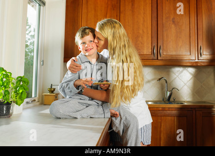 Frau küssen Junge Holding Sandwich in der Küche. Stockfoto