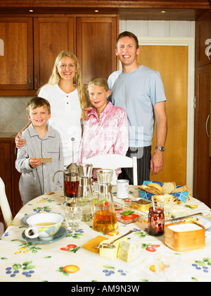 Familie stehen in Küche lächelnd mit dem Frühstück am Tisch. Stockfoto