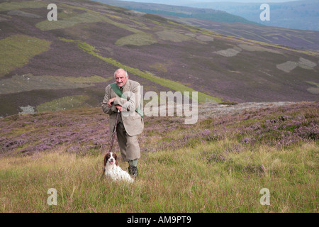 Wildhüter auf schottischem Heidekraut in Braemar, Cairngorms National Park, Royal Deeside, Schottland. VEREINIGTES KÖNIGREICH. Keeper mit Spaniel Retriever Wildhund. Stockfoto