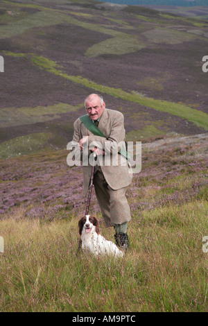 Wildhüter auf schottischem Heidekraut in Braemar, Cairngorms National Park, Royal Deeside, Schottland. VEREINIGTES KÖNIGREICH. Keeper mit Spaniel Retriever Wildhund. Stockfoto