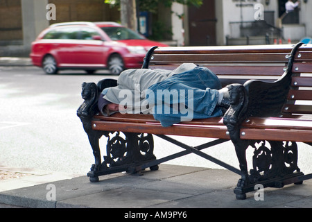 Obdachloser schläft auf der Bank am Bahndamm London Stockfoto