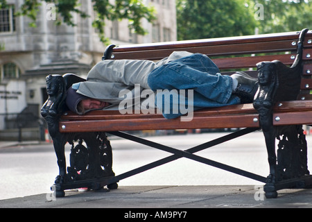 Obdachloser schläft auf der Bank am Bahndamm London Stockfoto