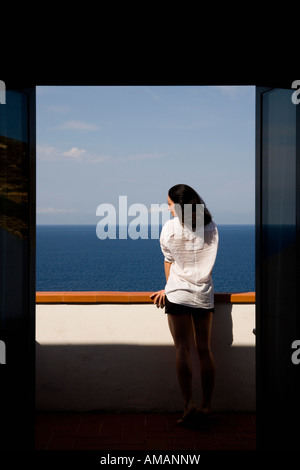 Eine Frau steht auf einem Balkon mit Blick auf das Meer Stockfoto